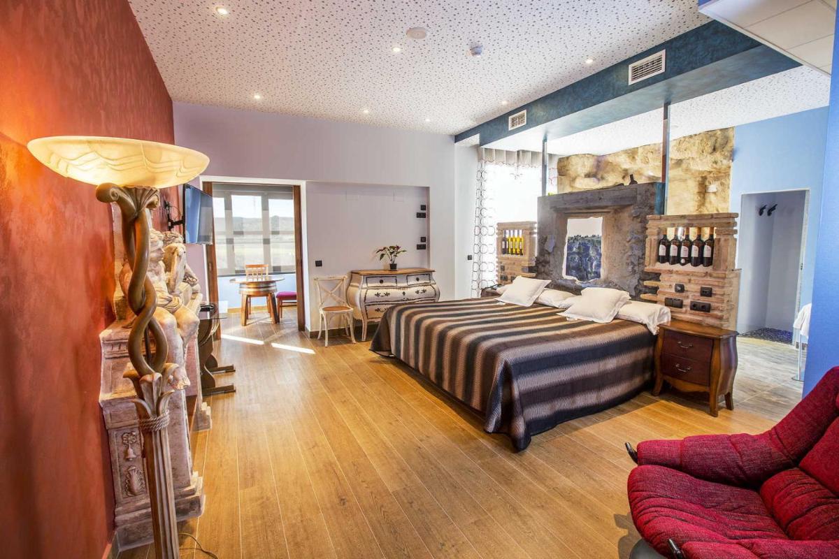 Un dormitorio con una cama y una sala de estar. en Hotel SPA El Lagar de Isilla, en La Vid y Barrios 125 fotos más