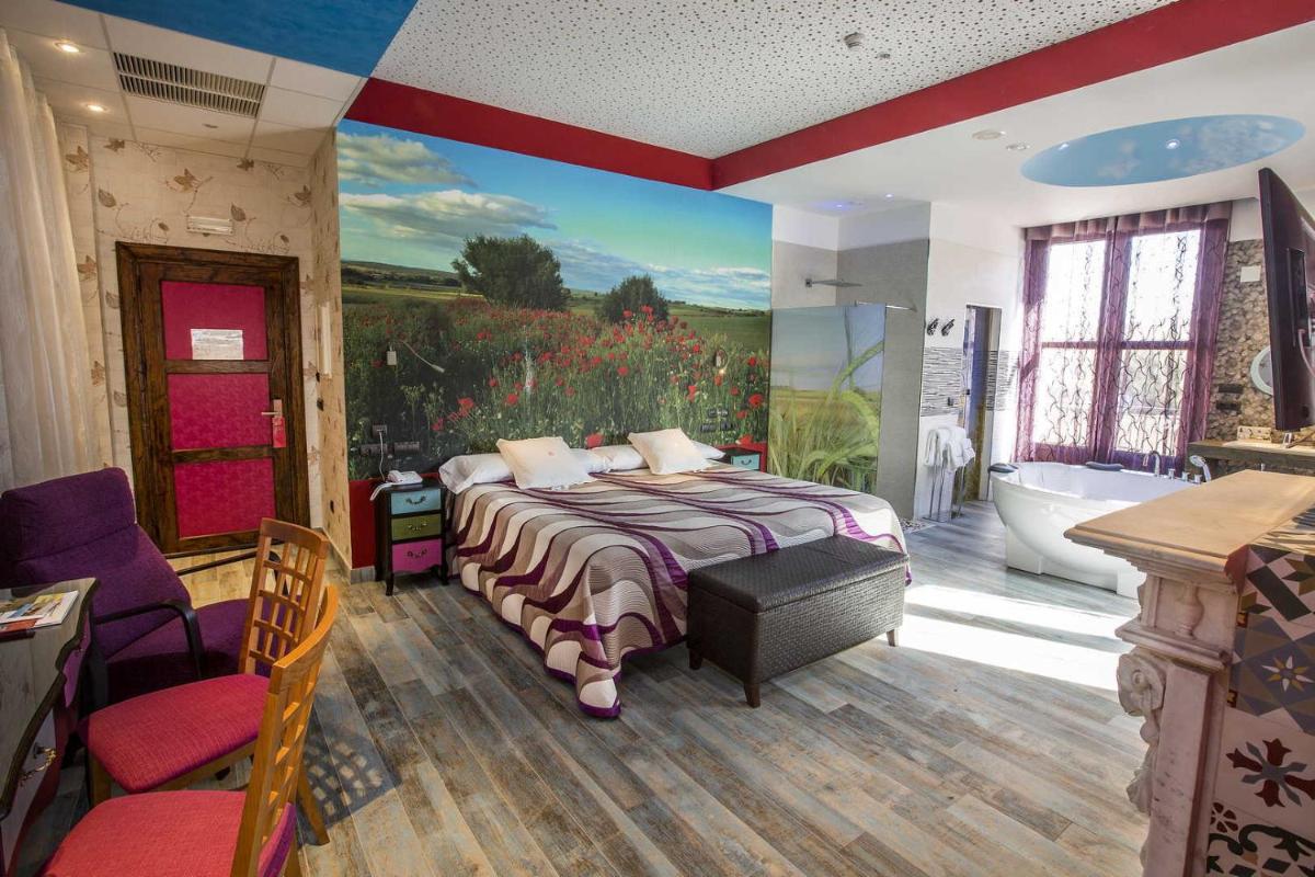 Un dormitorio con una cama y un baño con bañera. en Hotel SPA El Lagar de Isilla, en La Vid y Barrios