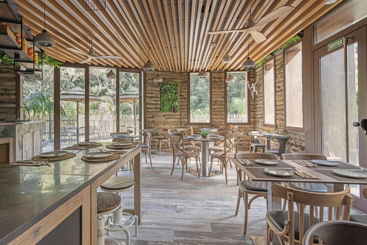 Un restaurante con techos de madera y mesas y sillas. en Casa Coco Boutique Hotel & Spa 4*S - Adults Only, en Lloret de Mar