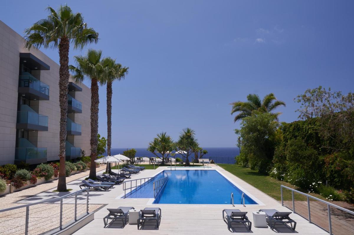 uma piscina com espreguiçadeiras e palmeiras em Golden Residence Hotel no Funchal