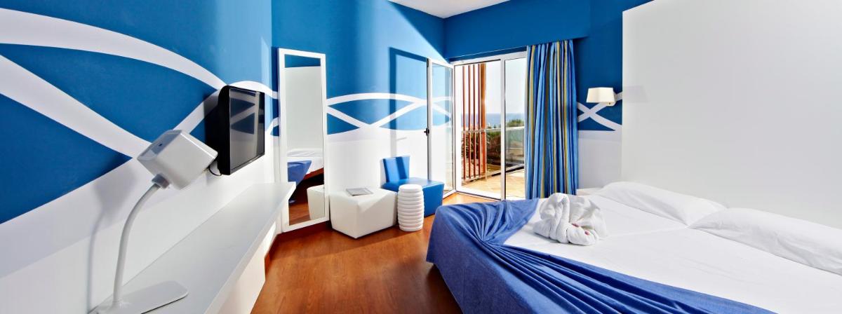 Habitación azul con cama y TV en Hotel Clumba, en Cala Ratjada