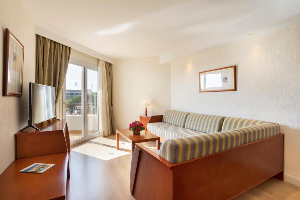 Una sala de estar con un sofá y un televisor. en Hipotels Dunas Aparthotel, en Cala Millor