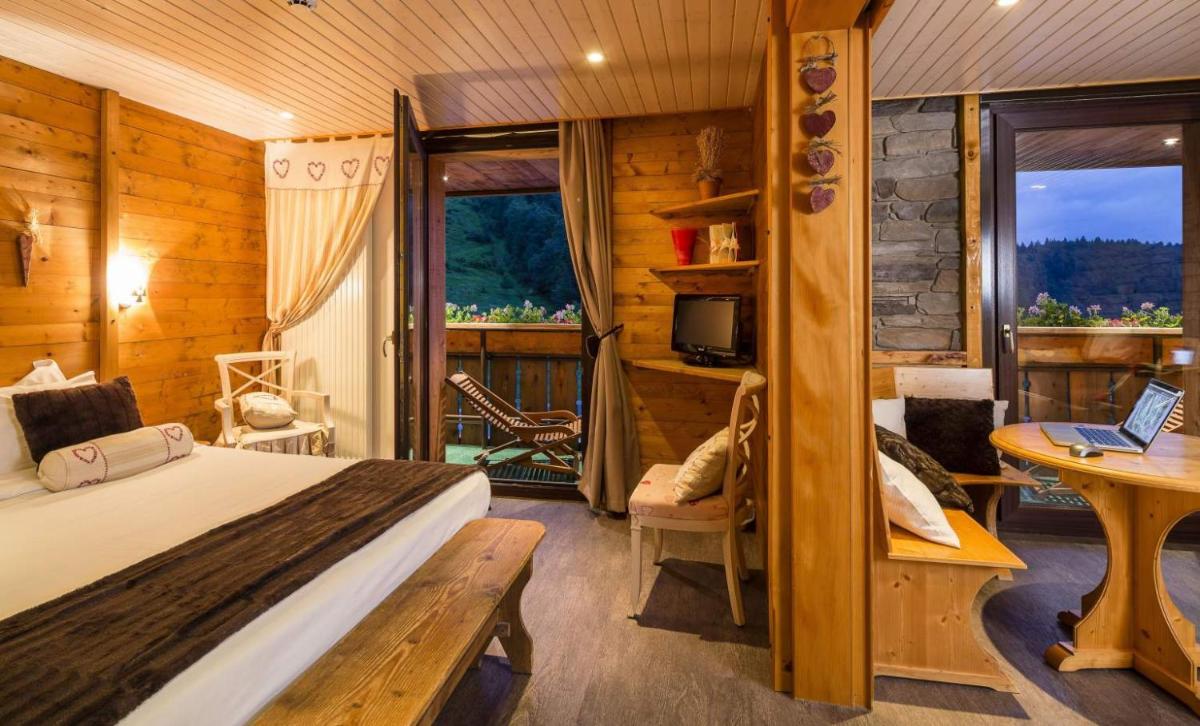 une chambre avec un lit et une table avec un ordinateur portable dans l'établissement Chalet Hôtel & Spa Le Collet, à Xonrupt-Longemer