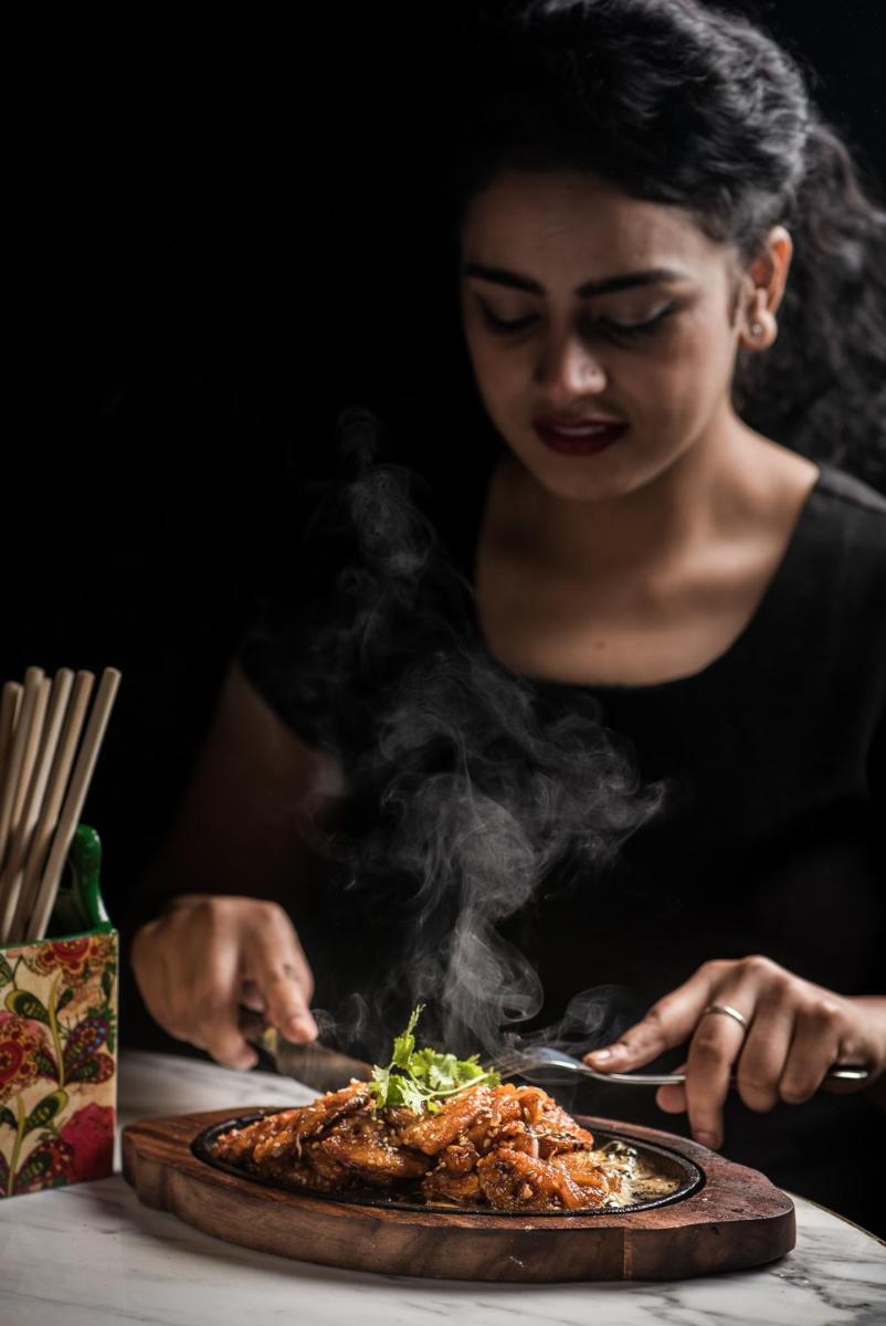 a woman is looking at a plate of food at Park Hyatt Hotel and Residences, Hyderabad in Hyderabad