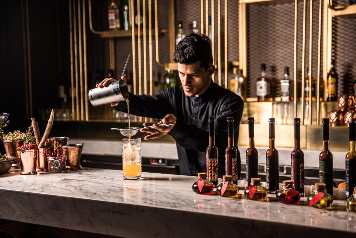 a man standing behind a bar making a drink at Park Hyatt Hotel and Residences, Hyderabad in Hyderabad