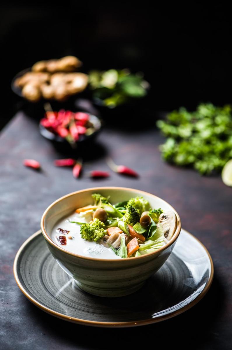 a bowl of soup with broccoli on a plate at Park Hyatt Hotel and Residences, Hyderabad in Hyderabad