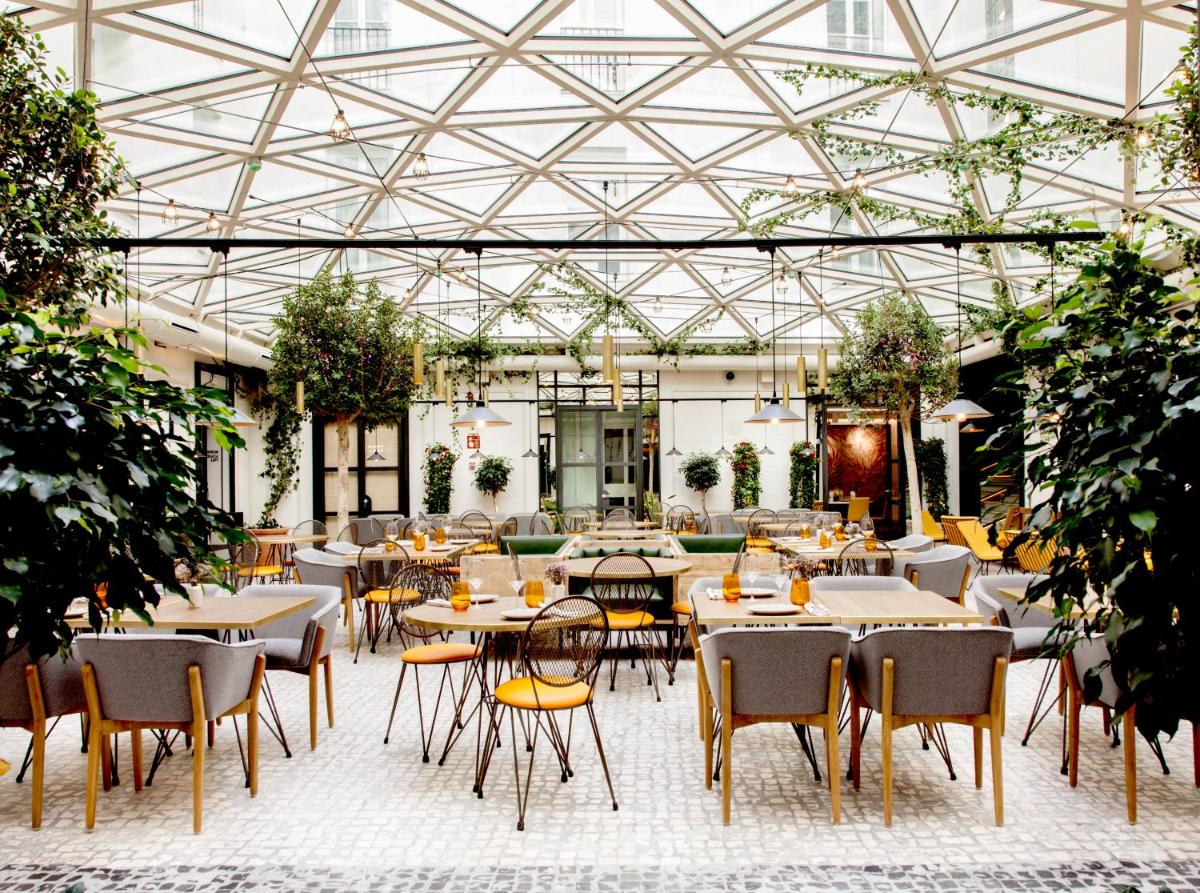 Un restaurante con mesas y sillas en un invernadero. en Pestana Collection Plaza Mayor, en Madrid
