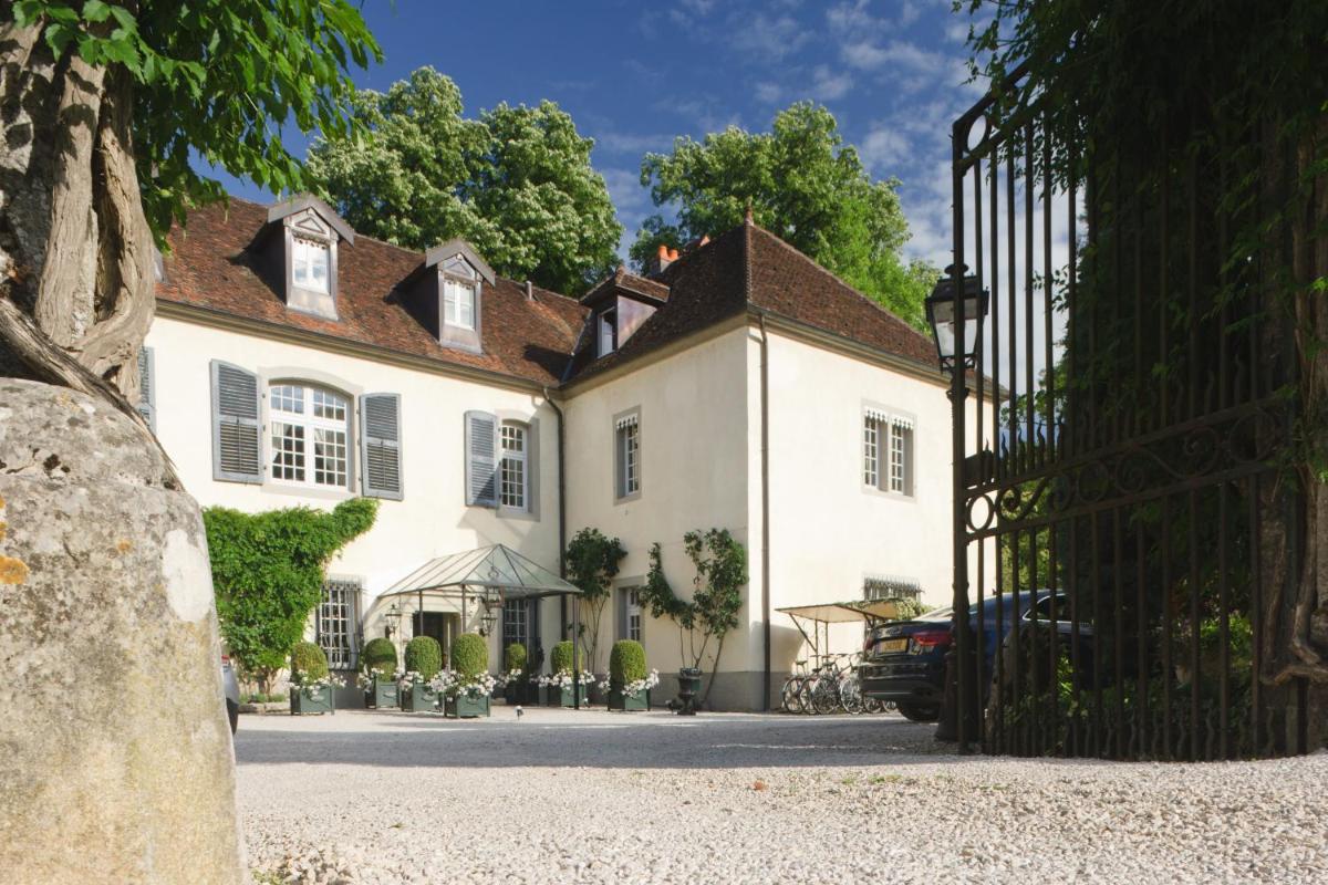 une grande maison blanche avec un portail noir dans l'établissement Chateau De Germigney, à Port-Lesney