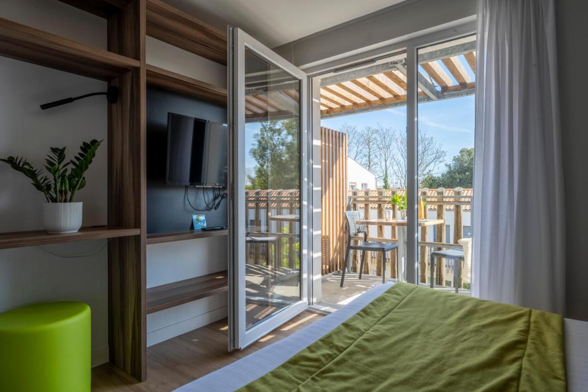 Cet appartement comprend une chambre avec un lit et un balcon avec une télévision. dans l'établissement ATHOME RESIDENCE ET SPA, à La Rochelle 75 autres photos