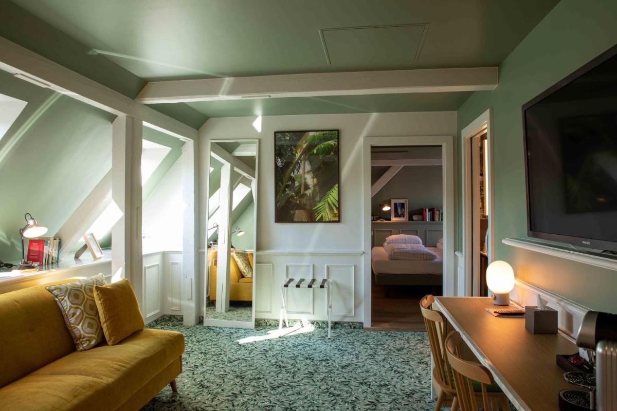 un salon avec un canapé et une télévision dans l'établissement Hôtel et Spa La Villa K - Basel Airport, à Saint-Louis