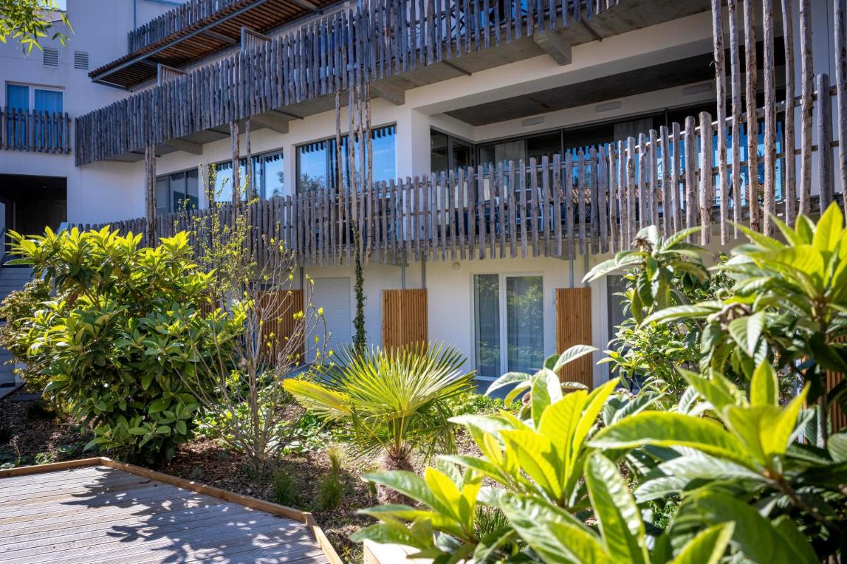 une vue extérieure d'un bâtiment avec des plantes dans l'établissement ATHOME RESIDENCE ET SPA, à La Rochelle