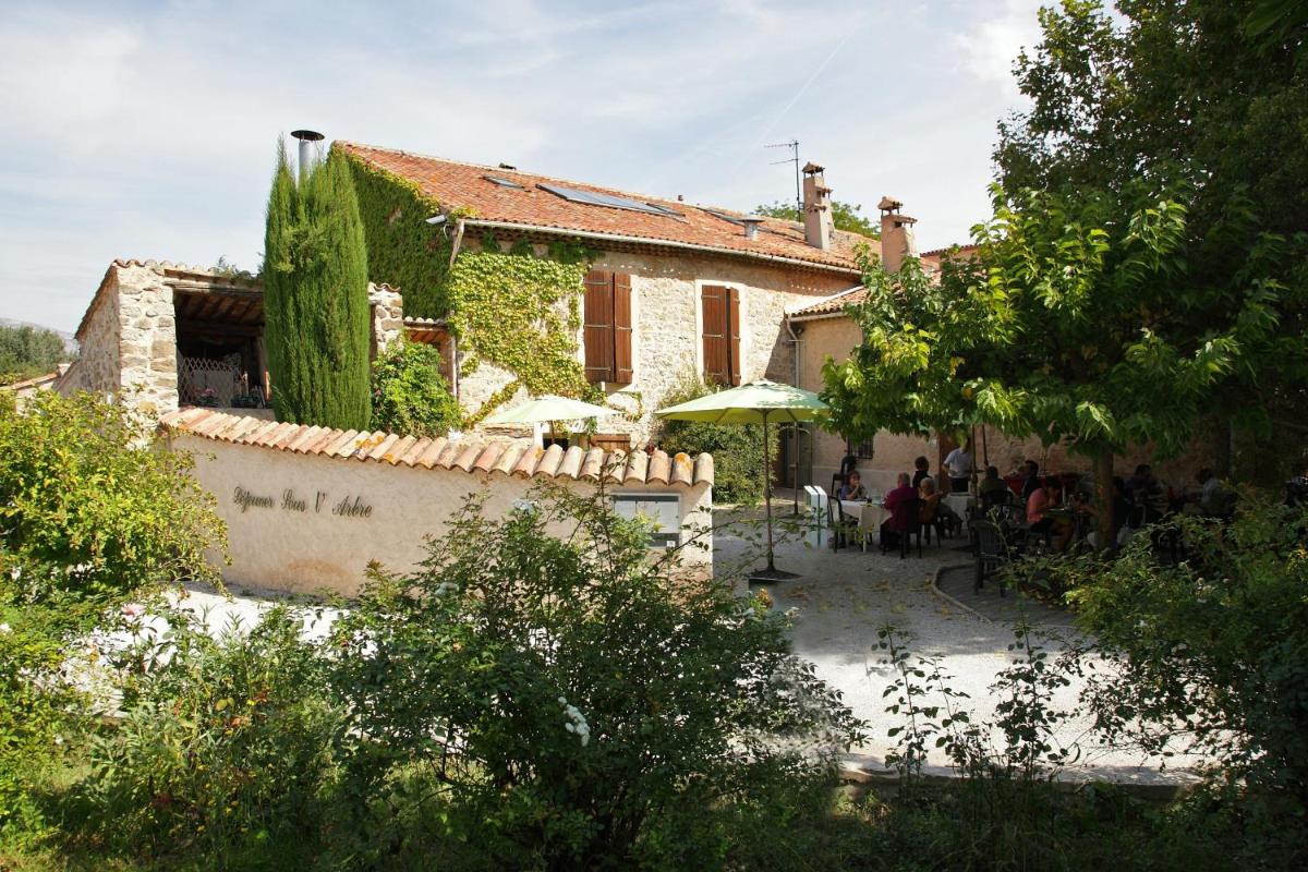 un bâtiment avec des gens assis à l'extérieur dans l'établissement Logis Hôtel & Spa Déjeunez Sous L'Arbre, à Rousset