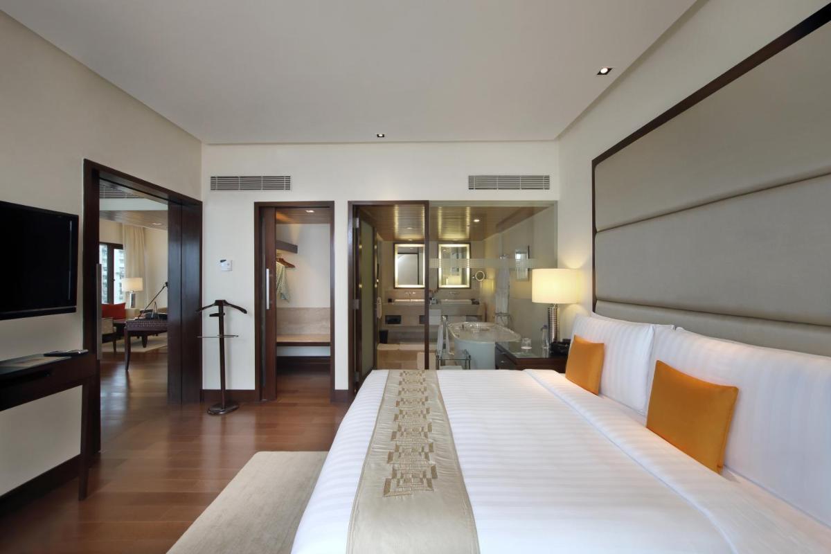 a bedroom with a large white bed and a bathroom at The Oberoi Mumbai in Mumbai