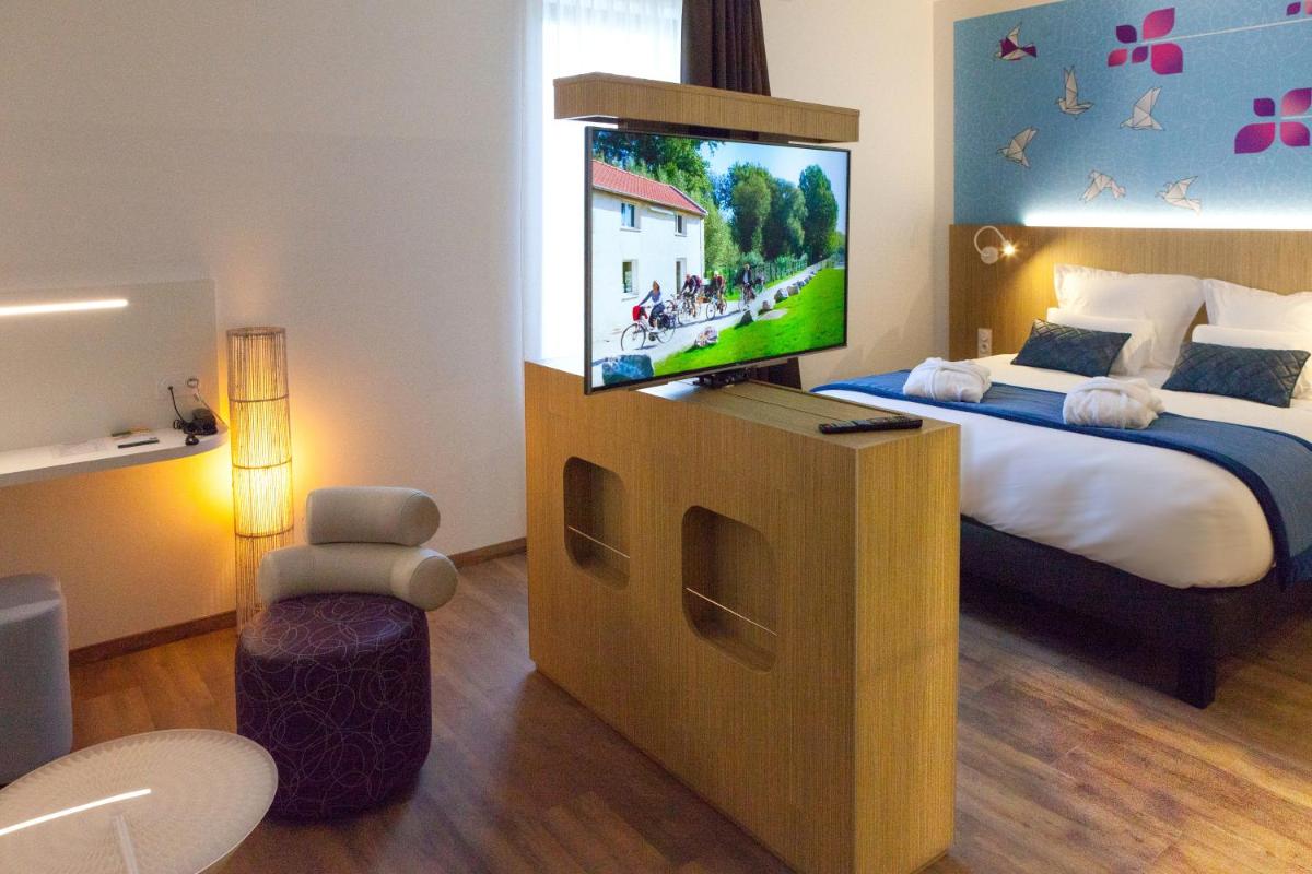 une chambre avec un lit et une télévision à écran plat dans l'établissement Kyriad Prestige Amiens Poulainville - Hotel and Spa, à Poulainville