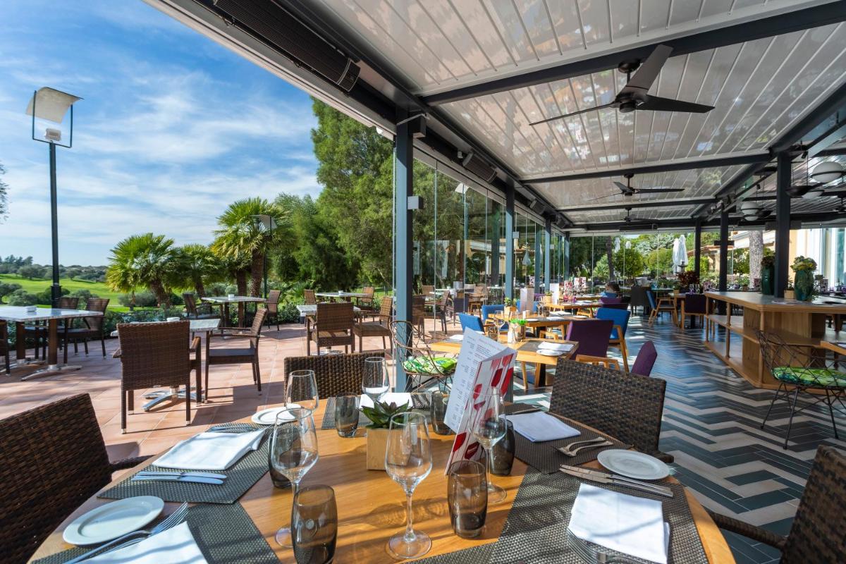Un restaurante con mesas y sillas y un patio. en Barceló Montecastillo Golf, en Jerez de la Frontera