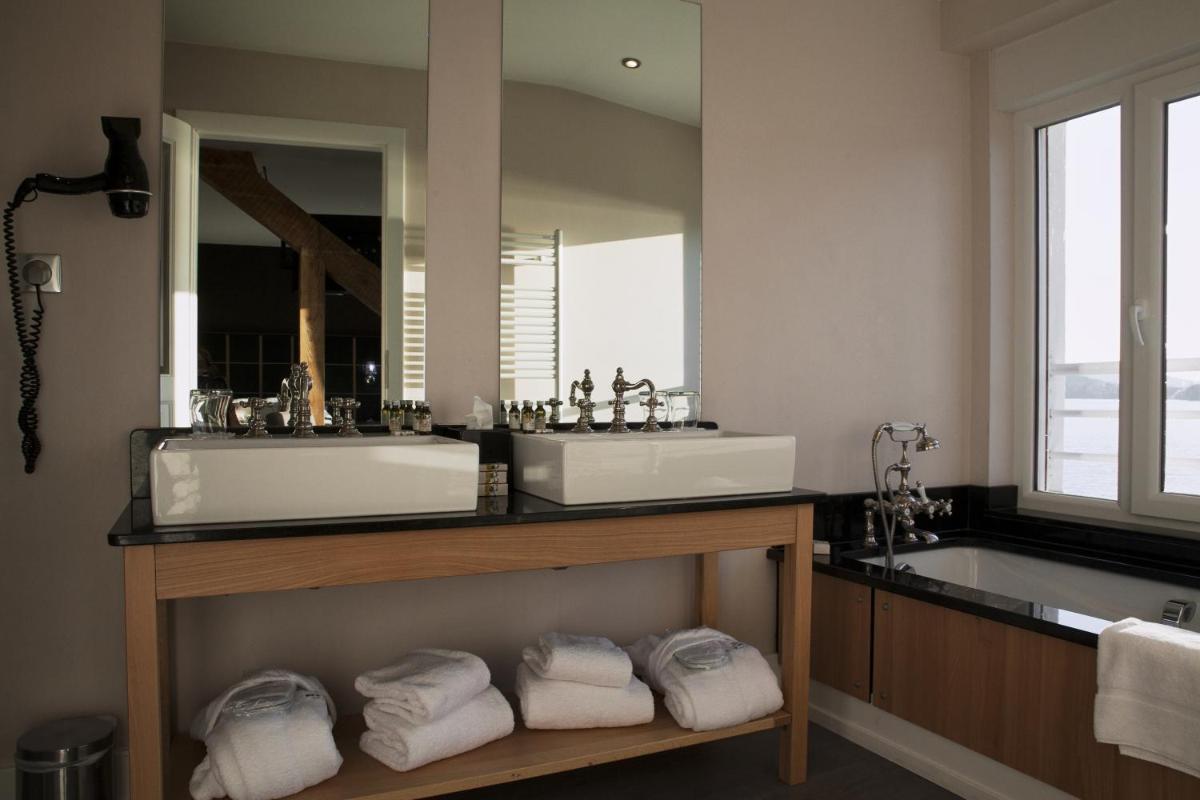 une salle de bains avec deux lavabos, un miroir et des serviettes dans l'établissement Hôtel Beau Rivage, à Gérardmer