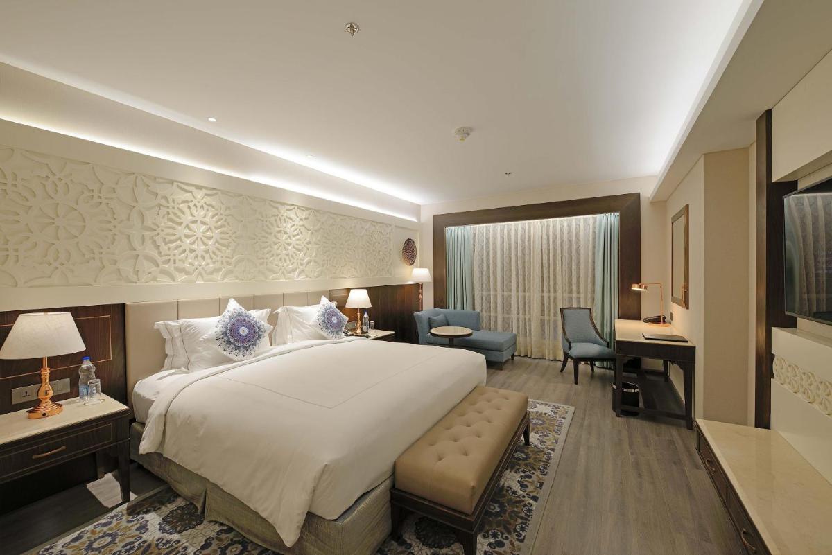 a hotel room with a large bed and a desk at Taj Skyline Ahmedabad in Ahmedabad