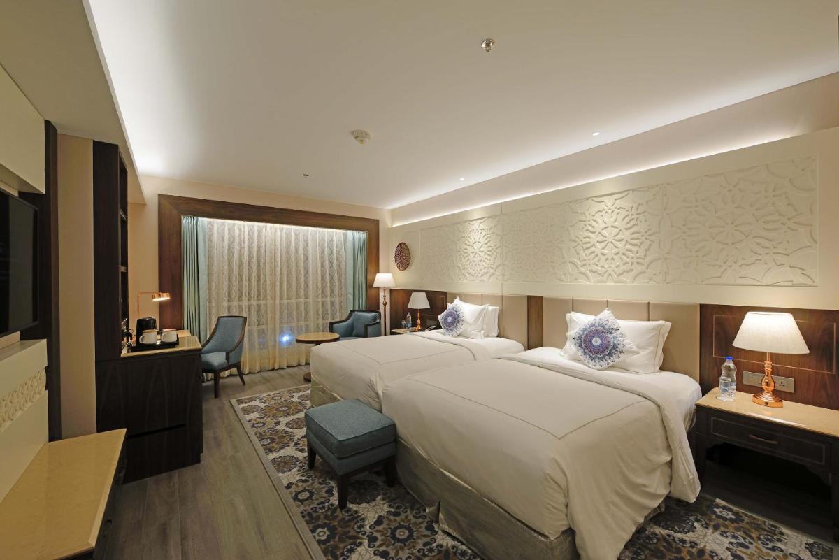 a hotel room with two beds and a desk at Taj Skyline Ahmedabad in Ahmedabad