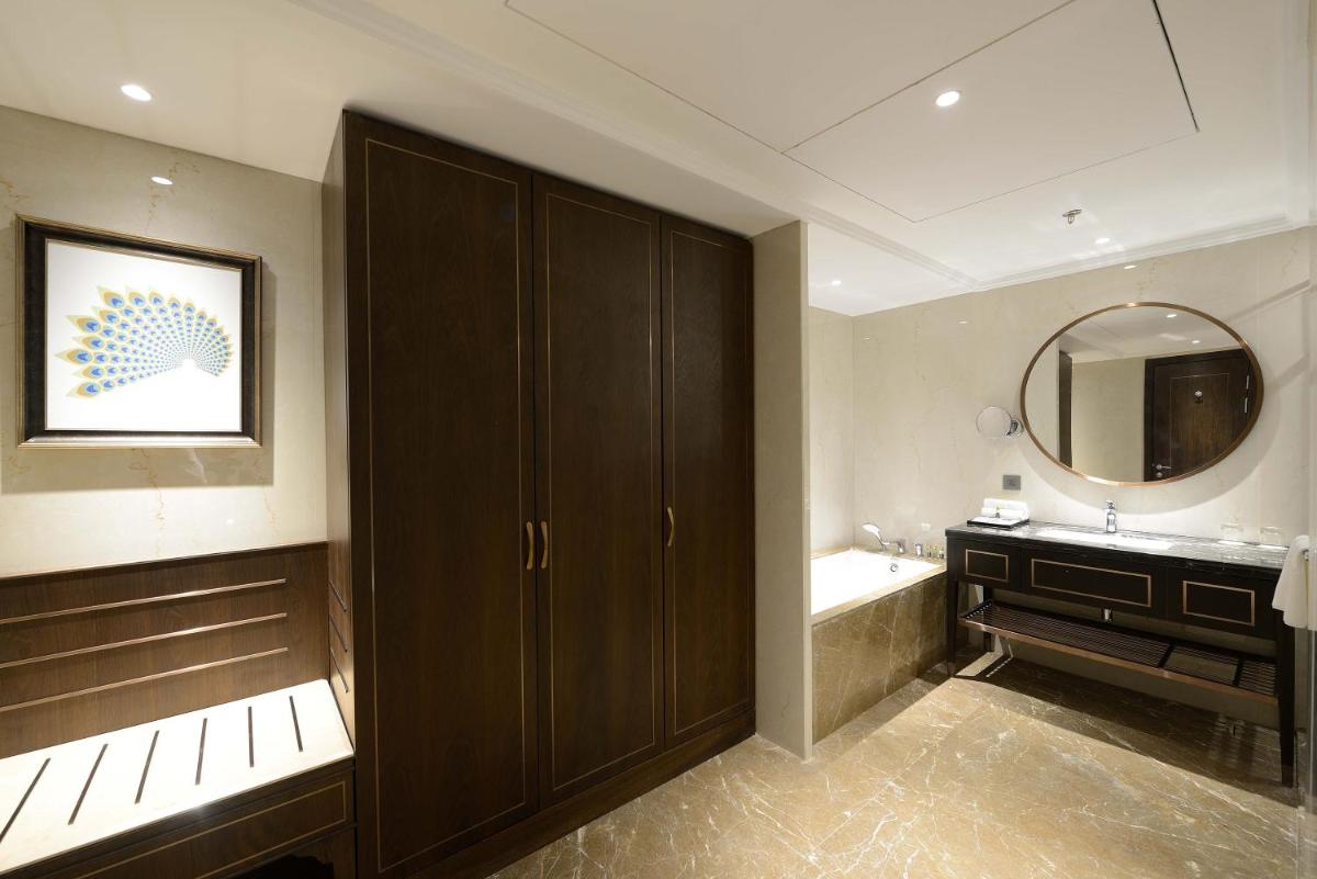 a bathroom with a sink and a tub and a mirror at Taj Skyline Ahmedabad in Ahmedabad