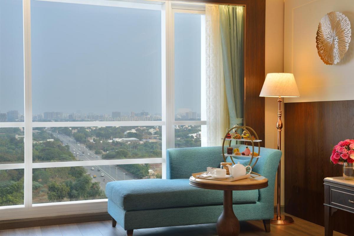 a room with a blue chair and a large window at Taj Skyline Ahmedabad in Ahmedabad