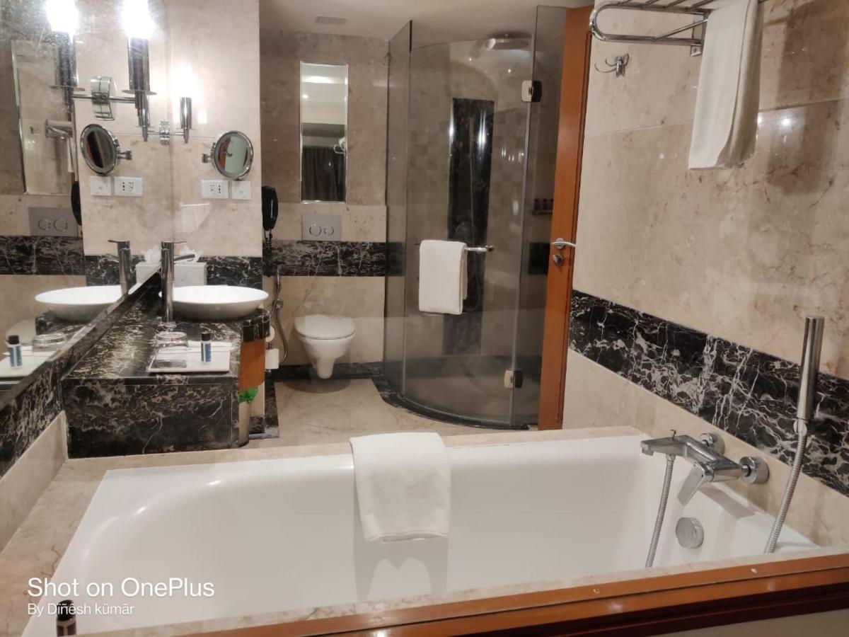 a bathroom with a tub and a sink and a toilet at Gokulam Grand Hotel & Spa Bangalore in Bengaluru a bathroom with a tub and a sink and a toilet at Gokulam Grand Hotel & Spa Bangalore in Bengaluru