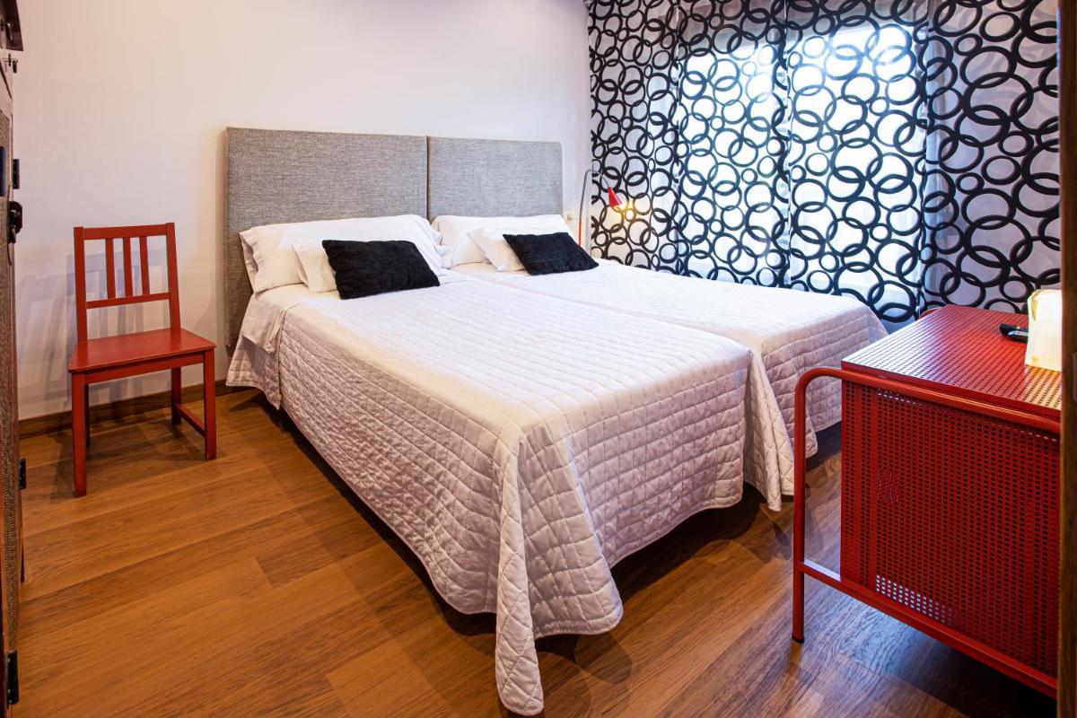 Un dormitorio con dos camas y una silla y una mesa. en LA CASONA Encanto Rural - ApartaHotel SPA Llanes, en Llanes