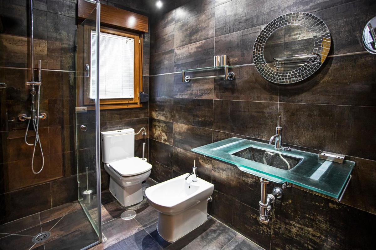 Un baño con inodoro, lavabo y ducha. en LA CASONA Encanto Rural - ApartaHotel SPA Llanes, en Llanes