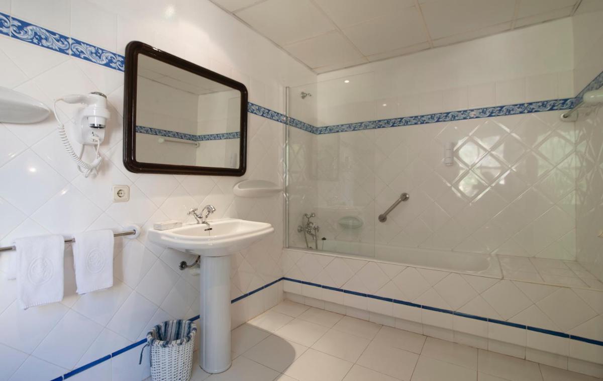 Un baño con lavabo, bañera y espejo. en Hotel Bahia, en Paguera