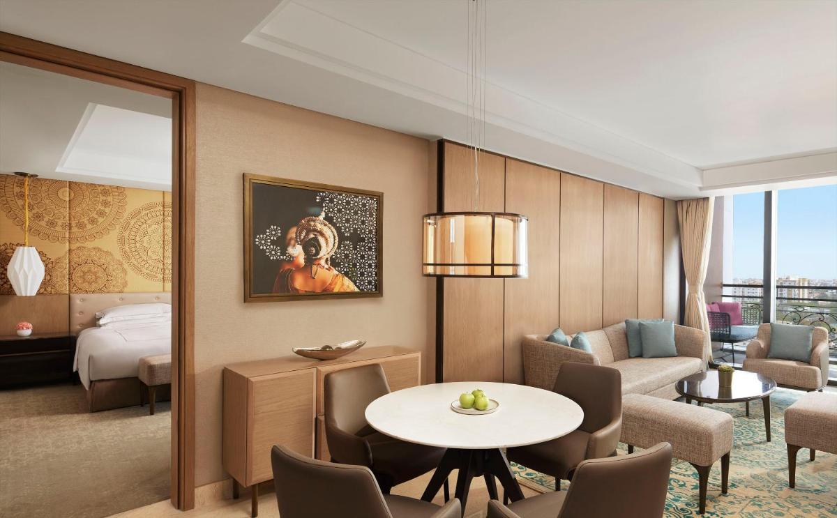 a hotel room with a bed and a table and chairs at Taj Wellington Mews Chennai in Chennai