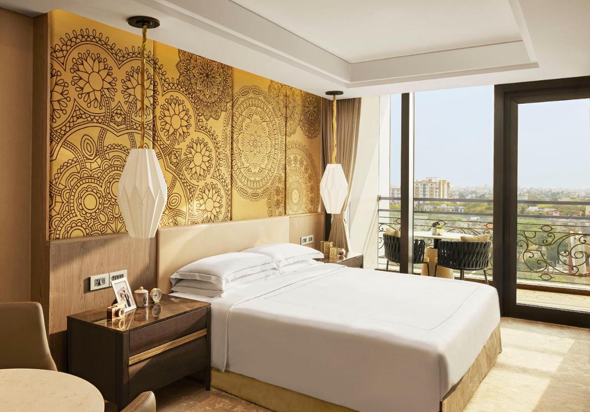a hotel room with a bed and a large window at Taj Wellington Mews Chennai in Chennai