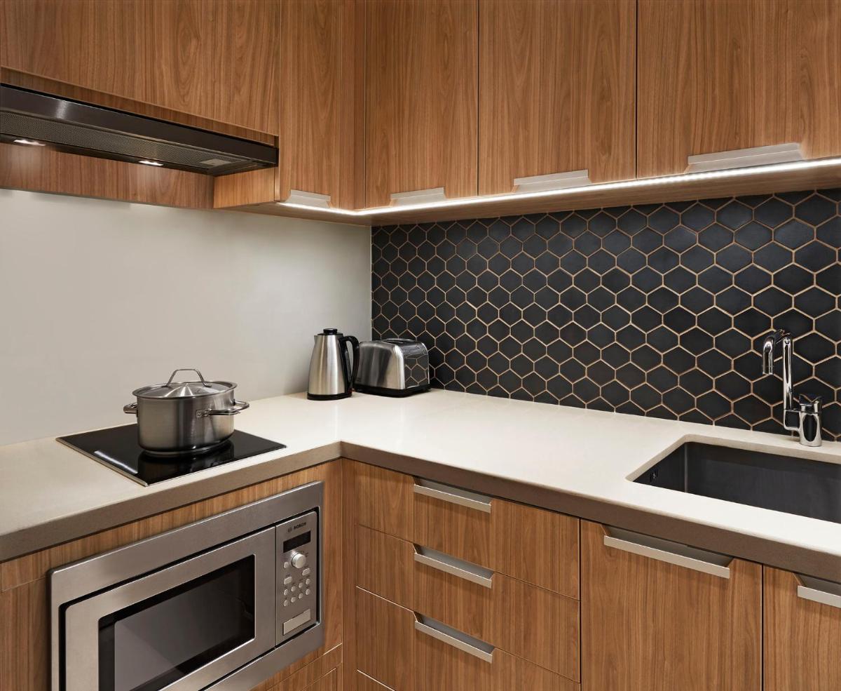 a kitchen with wooden cabinets and a stove top oven at Taj Wellington Mews Chennai in Chennai