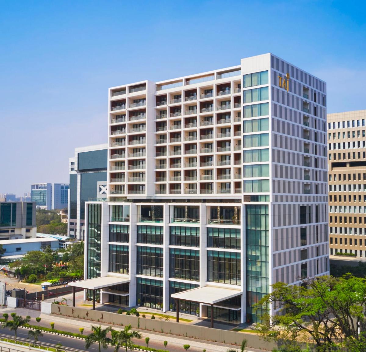 a tall white building with glass windows in a city at Taj Wellington Mews Chennai in Chennai