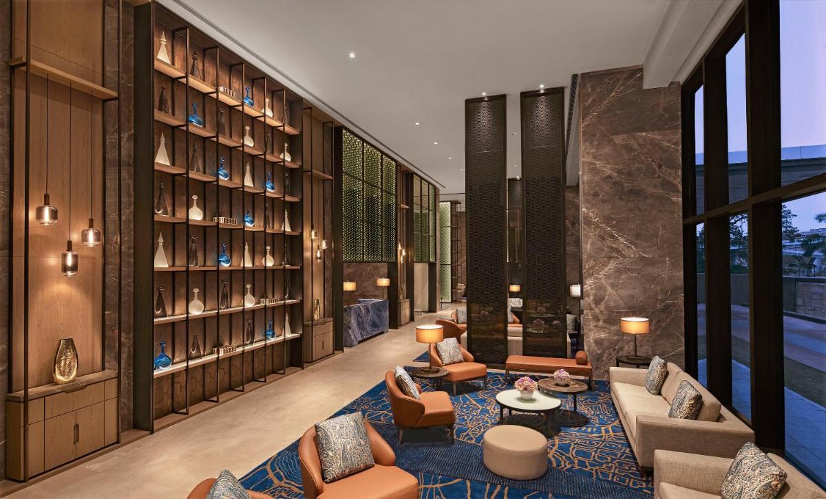 a hotel lobby with couches and chairs and books at Taj Wellington Mews Chennai in Chennai