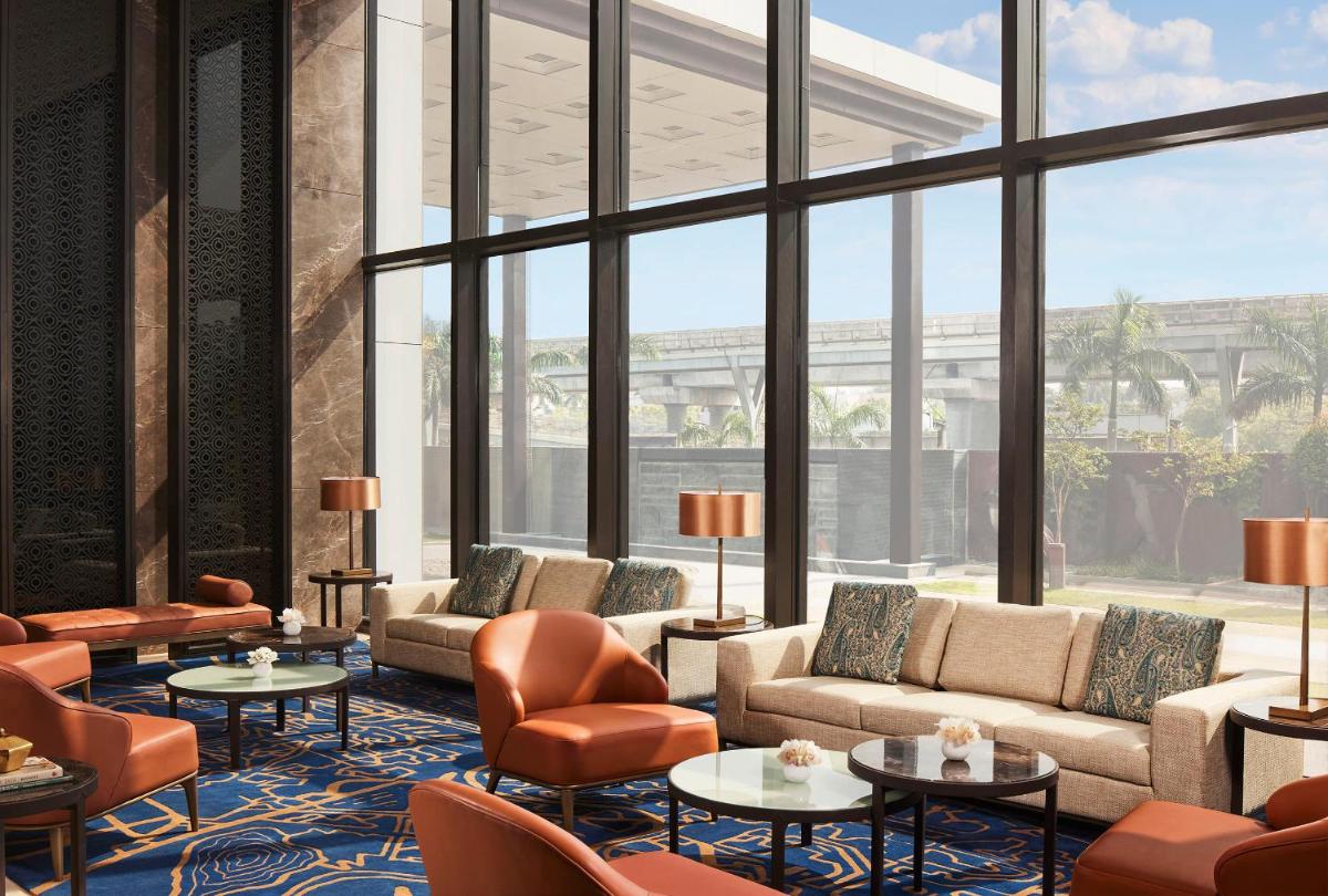 a lobby with couches and chairs and a large window at Taj Wellington Mews Chennai in Chennai