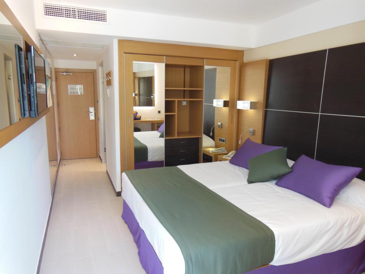 1 dormitorio con 1 cama grande con almohadas moradas y verdes en Hotel Isla de Cabrera, en Colonia de Sant Jordi 27 fotos más