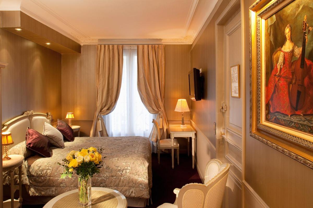 une chambre avec un lit et un vase de fleurs sur une table dans l'établissement Hotel & Spa Saint-Jacques, à Paris