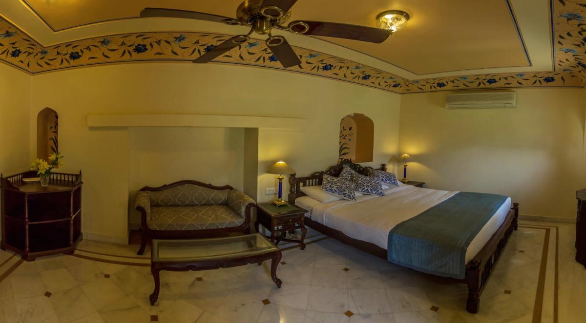 a bedroom with a bed and a couch and a ceiling fan at Royal Heritage Haveli - By Leisure Hotels in Jaipur