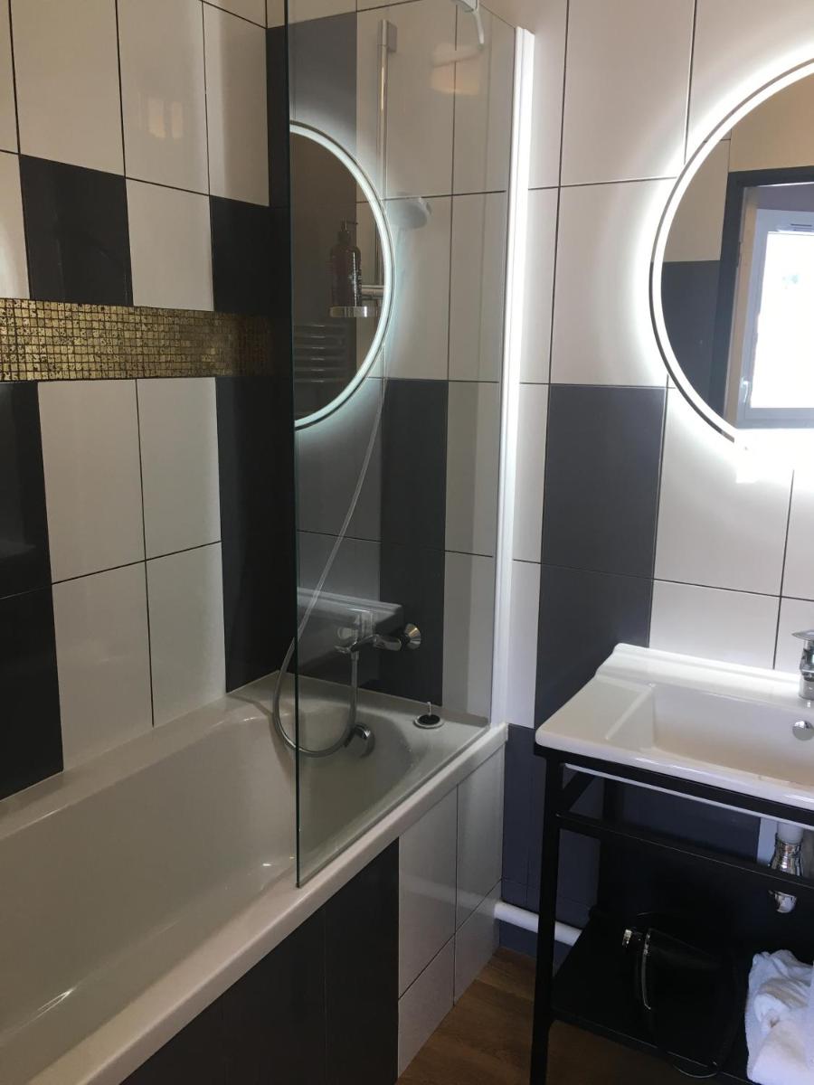 une salle de bains avec baignoire, lavabo et miroir dans l'établissement Résidence-Aïga Resort thermal & spa, à Châtel-Guyon