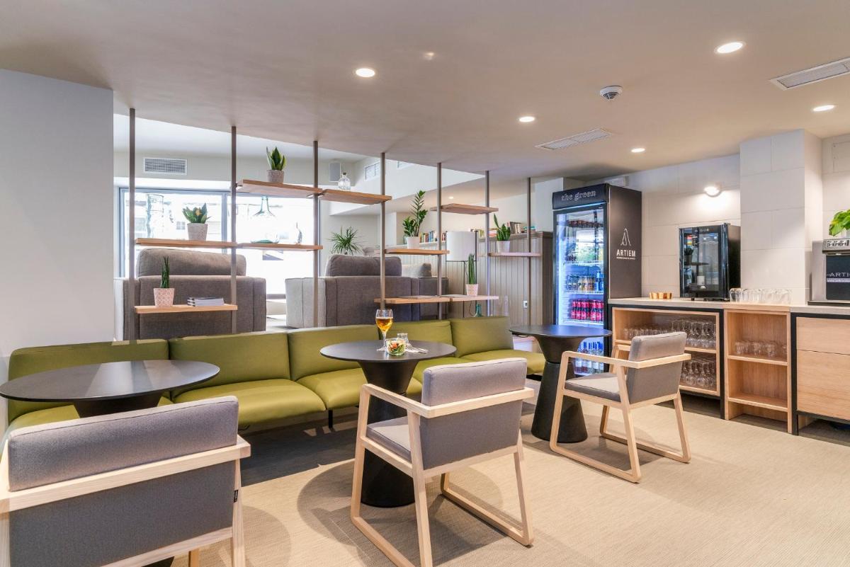 Un restaurante con un sofá verde, mesas y sillas. en ARTIEM Capri, en Mahón