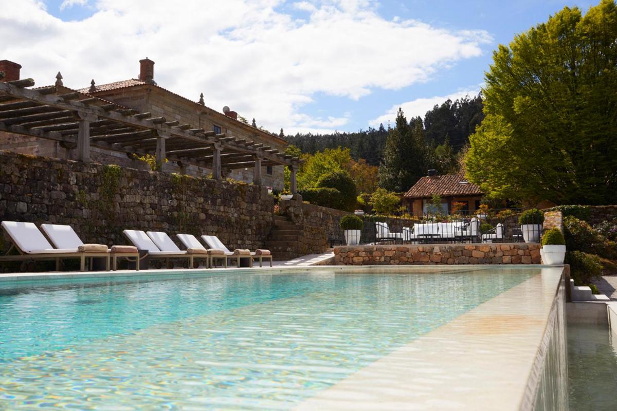 Una piscina con tumbonas y un muro de piedra. en Helguera Palacio Boutique & Antique, en Torrelavega