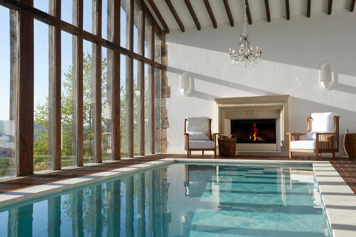 una piscina con 2 sillas y una chimenea en Helguera Palacio Boutique & Antique, en Torrelavega