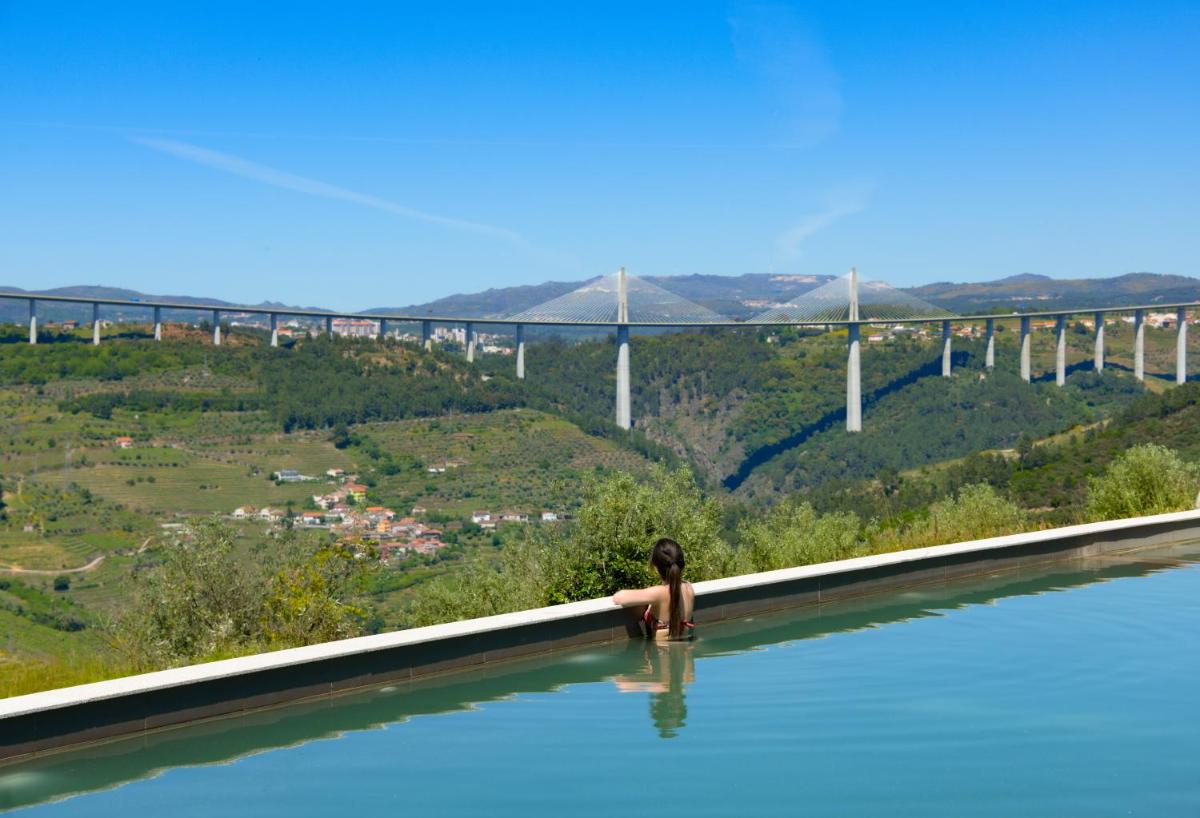 uma pessoa em uma piscina com uma ponte ao fundo em MW Douro Wine & Spa em Santa Marta de Penaguião
