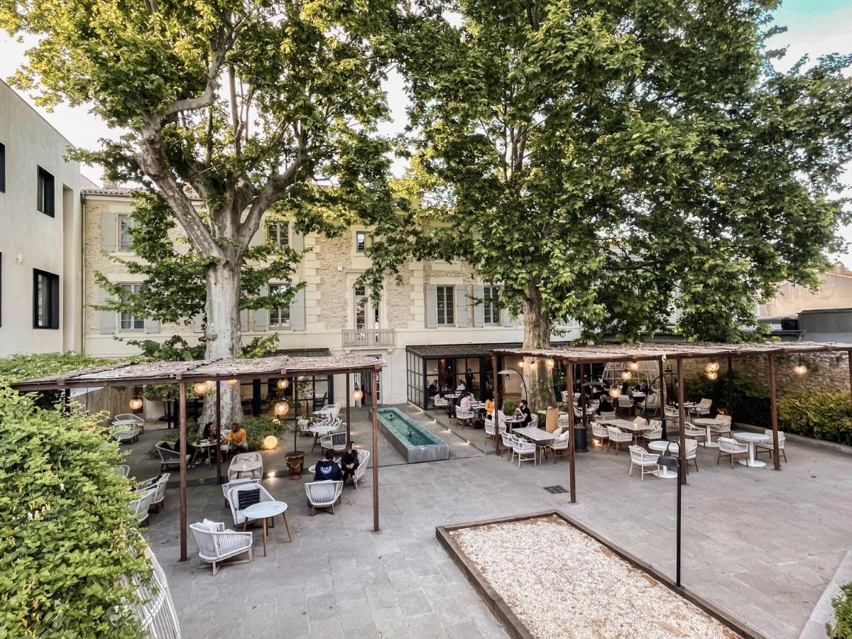 une terrasse extérieure avec tables, chaises et arbres dans l'établissement Hôtel Le Saint Remy & Spa, à Saint-Rémy-de-Provence