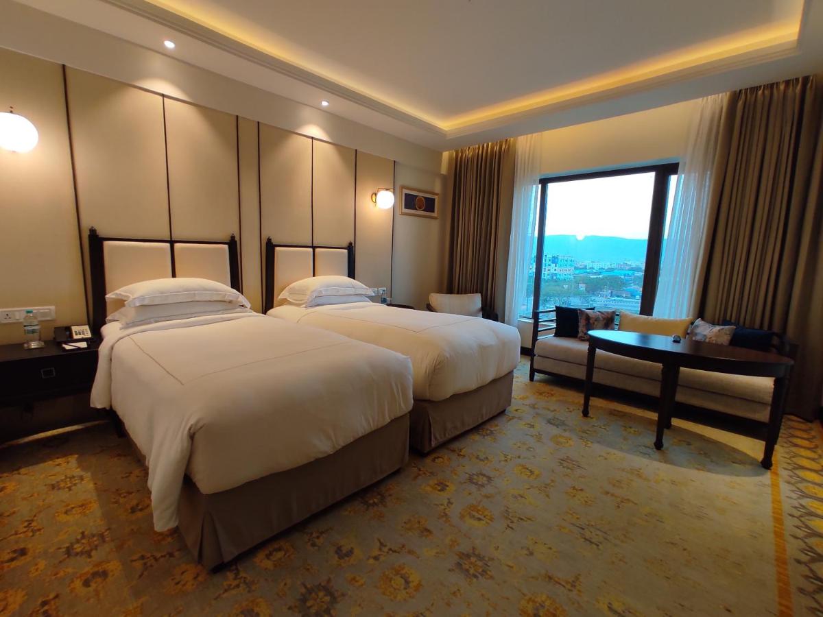 two beds in a hotel room with a large window at Taj Tirupati in Tirupati