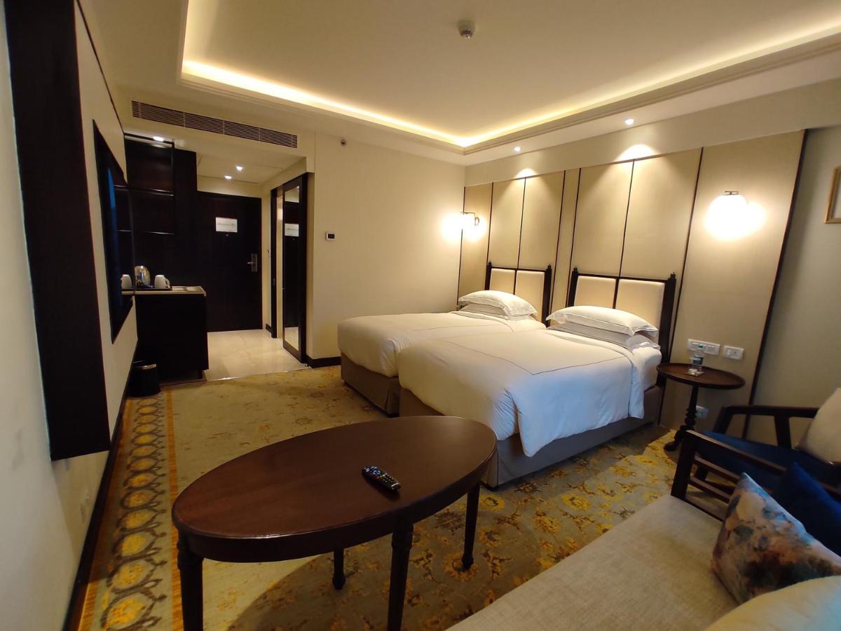 a hotel room with two beds and a coffee table at Taj Tirupati in Tirupati