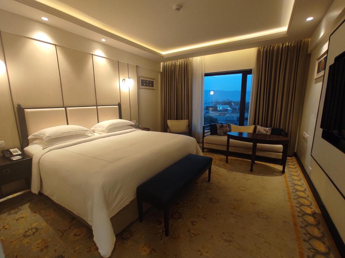 a hotel room with a large bed and a desk at Taj Tirupati in Tirupati
