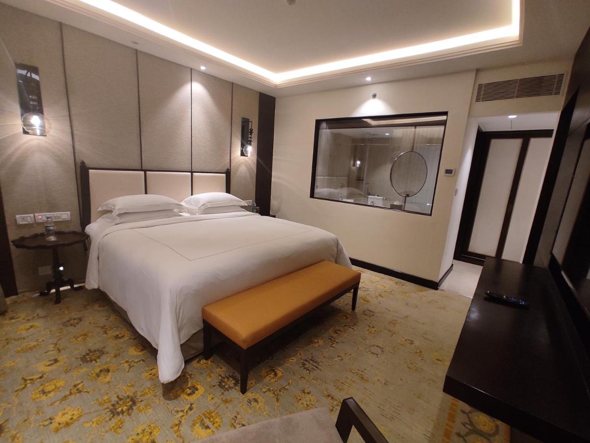 a bedroom with a large white bed and a mirror at Taj Tirupati in Tirupati