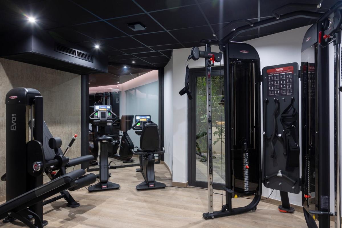 une salle de sport avec plusieurs tapis de course et machines à roulettes dans l'établissement Hotel L'Acquale, à Calvi