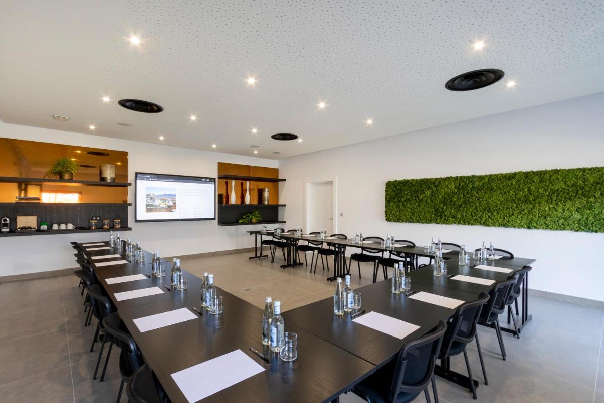 une salle de conférence avec des tables et des chaises et un mur vert dans l'établissement Hotel L'Acquale, à Calvi 91 autres photos