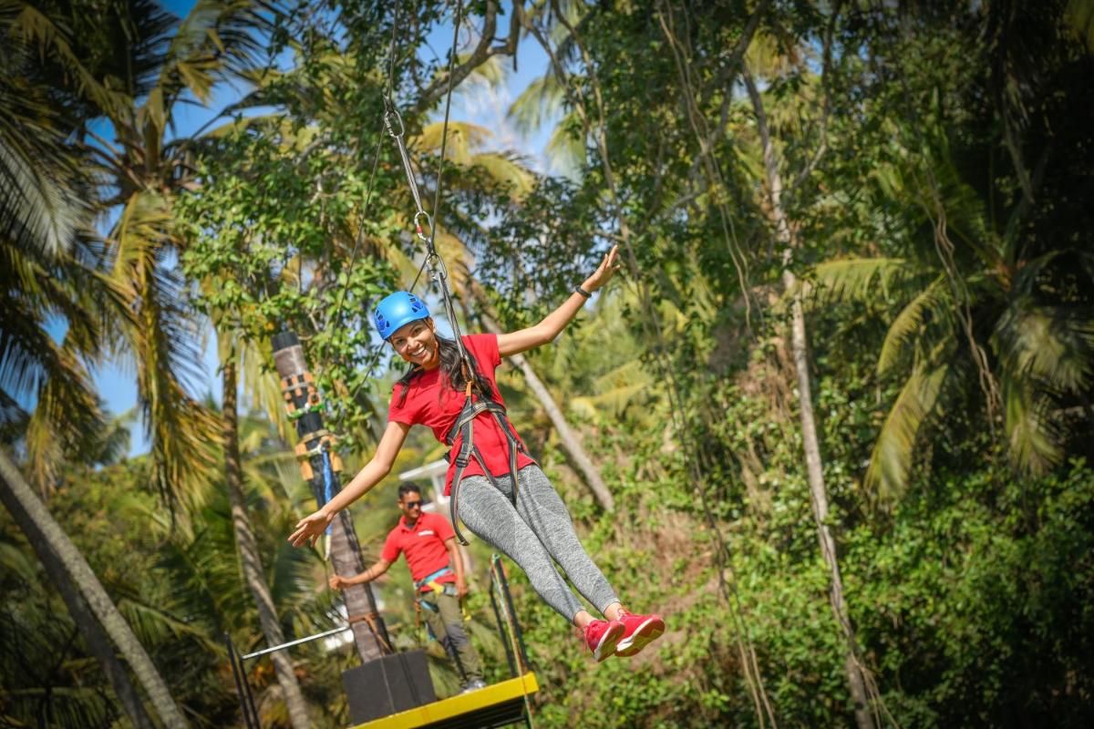 a woman jumping in the air on a zip line at Grand Hyatt Goa in Panaji a woman jumping in the air on a zip line at Grand Hyatt Goa in Panaji